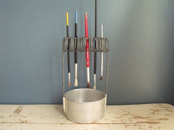 a metal cup sitting on top of a wooden table next to a toothbrush holder