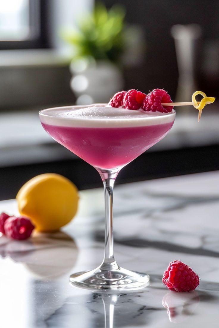 a raspberry martini is garnished with lemons and served on a marble table