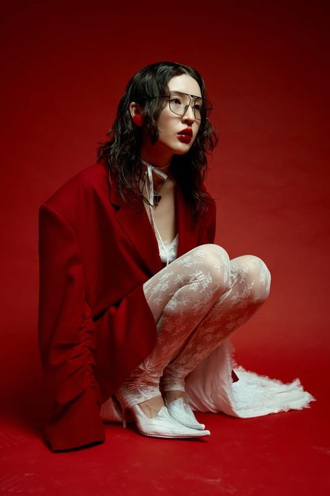 a woman with glasses is sitting on the floor wearing white stockings and high heels while posing for a photo