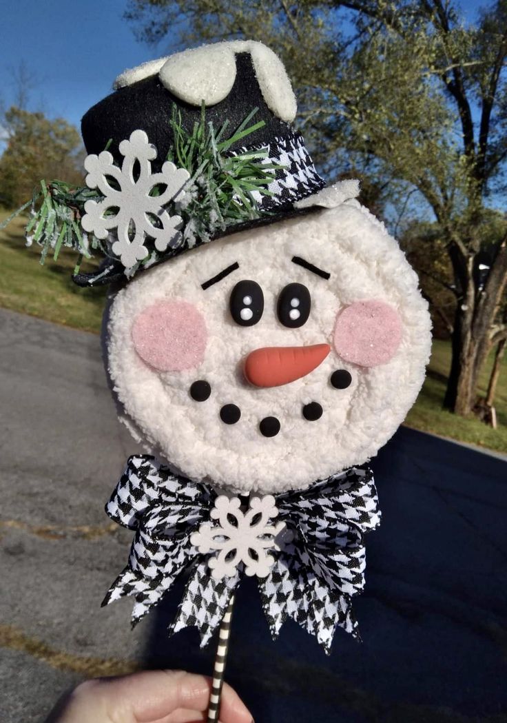 a hand holding a snowman ornament on the street