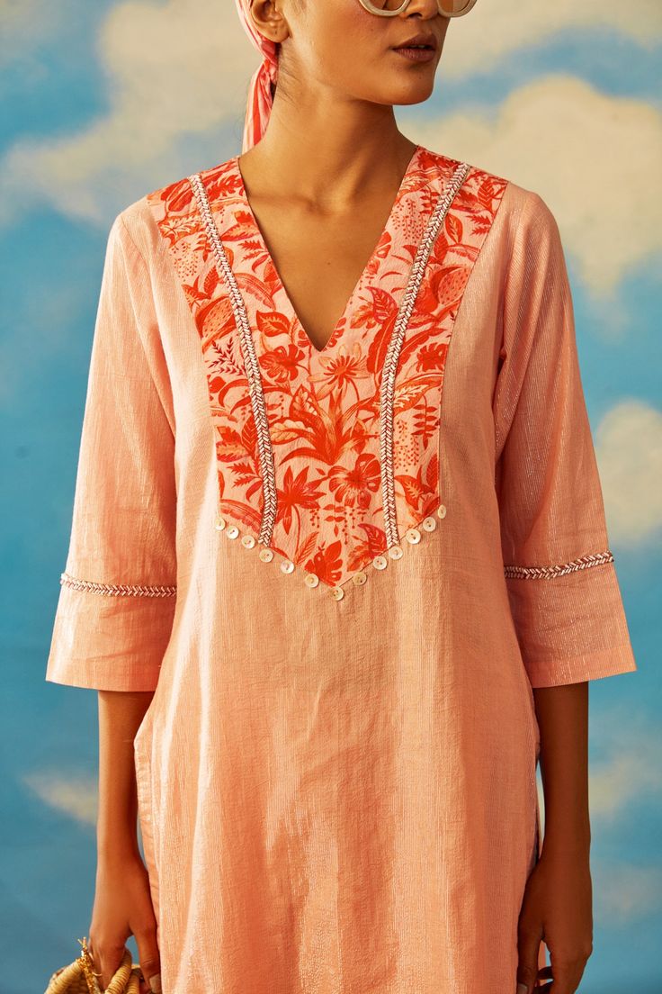 Coral cotton lurex kurta with floral print on the neckline and cutdana embroidery. Comes with palazzo pants. Component: 2 Pattern: Print and Embroidery Type Of Work: Floral Print and Cutdana Neckline: V neck Sleeve Type: Three Quarter Fabric: Lurex Color: Pink Other Details:  Button detail on the yoke Side slits Palazzo with striped panel at the hem Note: Hairband and bag carried by the model is not for sale Occasion: Puja - Aza Fashions Modern Kurta Designs Women, Women Kurtis Design Indian, Short Kurti Neck Designs, Unique Kurta Designs Women, Short Kurta With Pants, Rishi Vibhuti, Straight Kurti Designs, Suit Stitching, Simple Anarkali