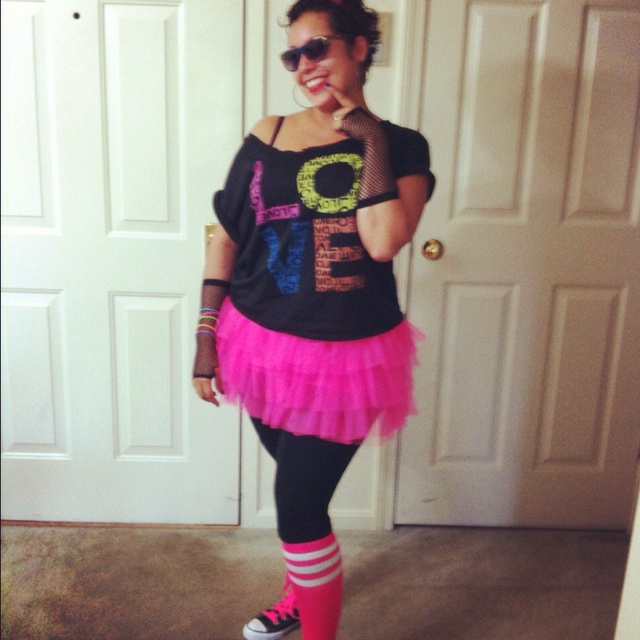 a woman wearing pink and black is posing for the camera in front of a door