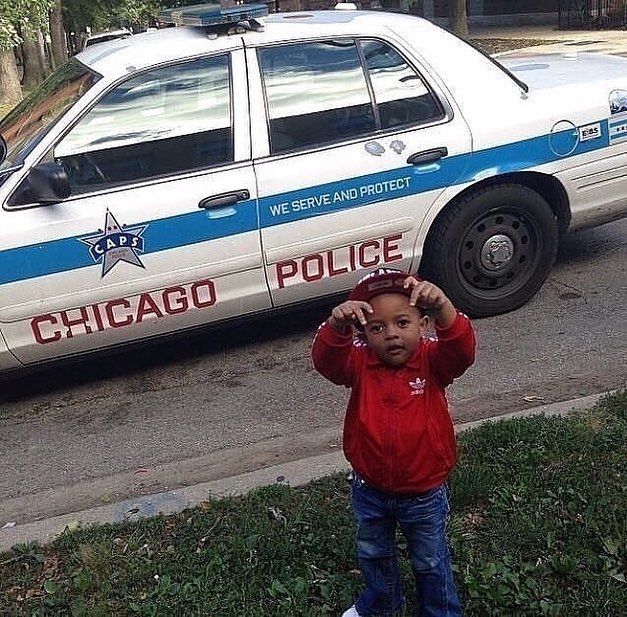 a young boy standing in front of a police car