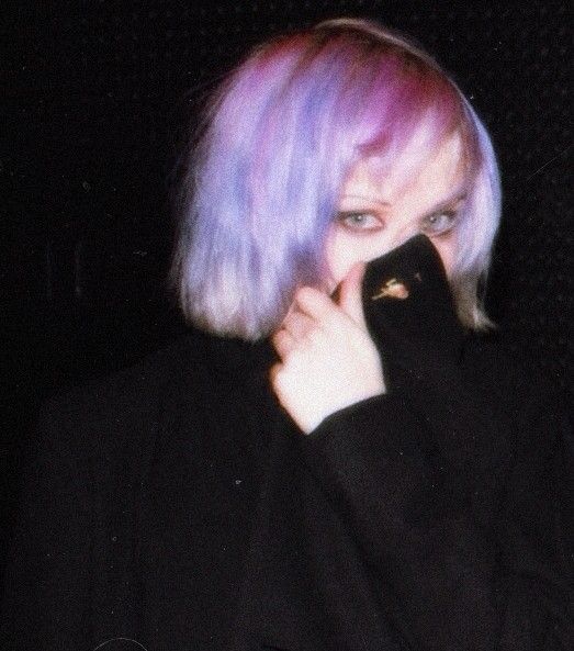 a woman with purple hair is covering her face