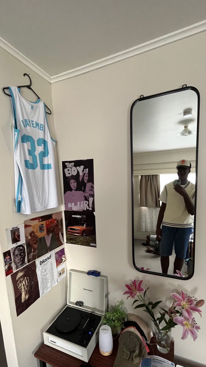 a man is reflected in a mirror next to a desk with a record player on it