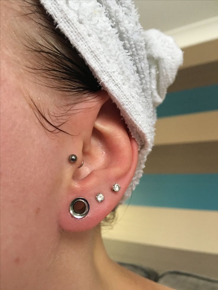 a close up of a person wearing ear piercings and a towel on their head