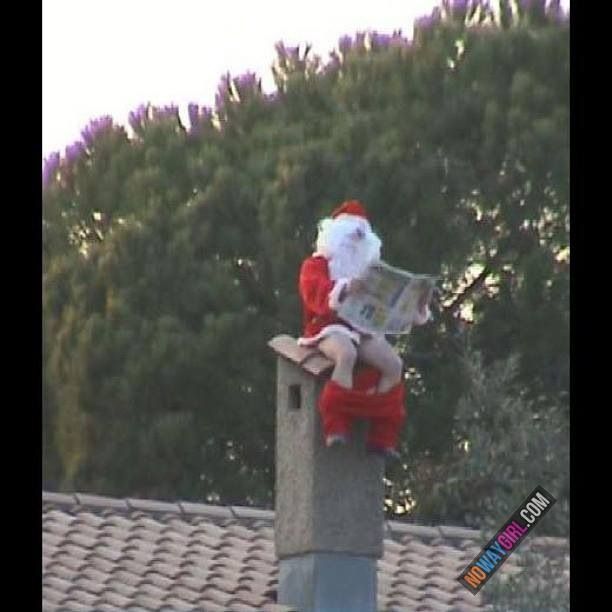 a santa clause sitting on top of a chimney reading a newspaper while wearing a red and white suit