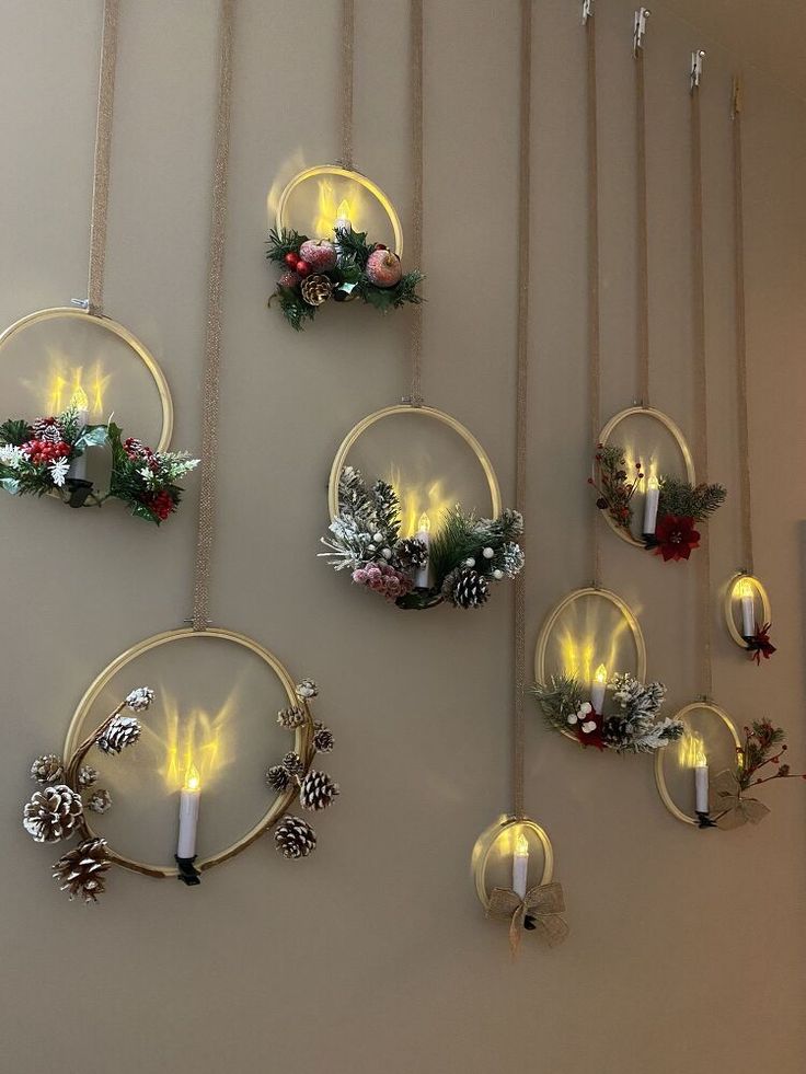 christmas decorations are hanging on the wall with candles and wreaths in circular glass holders