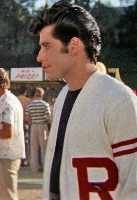 a man standing in front of a group of people at an outdoor event wearing a baseball uniform