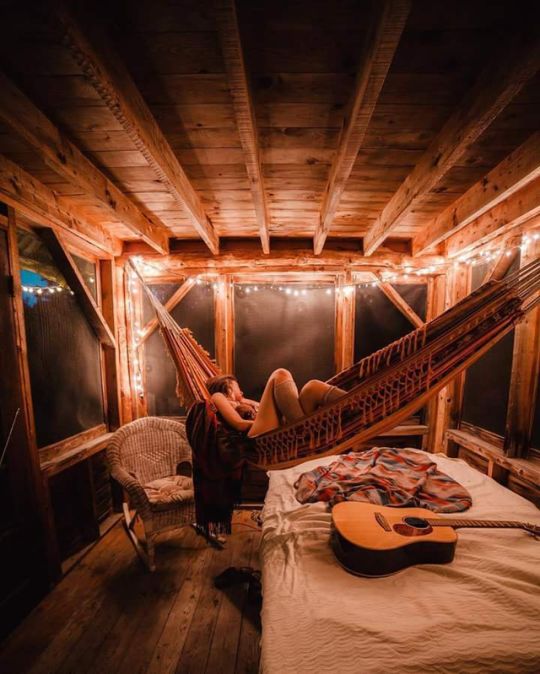 a person laying in a hammock on top of a bed next to a guitar