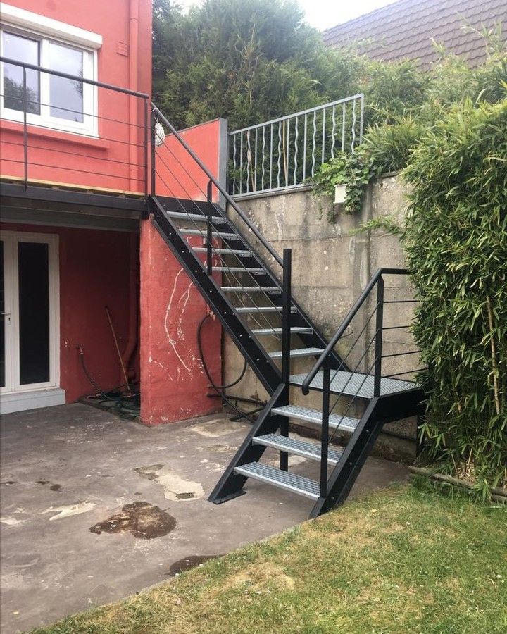 a metal stair case next to a red building