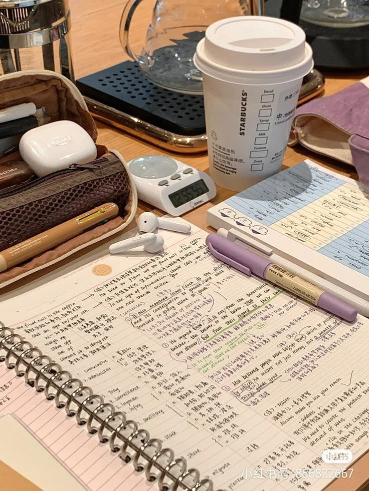 an open notebook sitting on top of a wooden table next to a cup of coffee