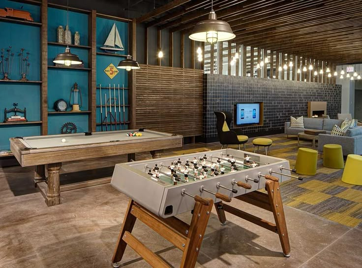 a living room filled with furniture and a foo - pong table in front of a flat screen tv