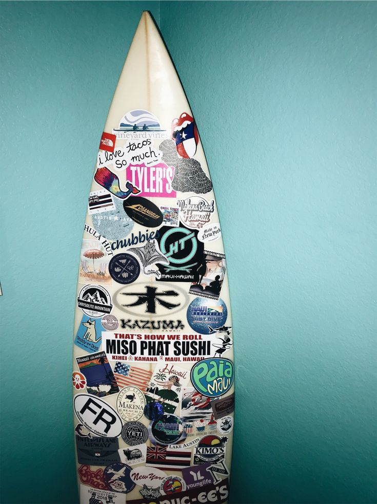 a surfboard covered in stickers on a blue wall