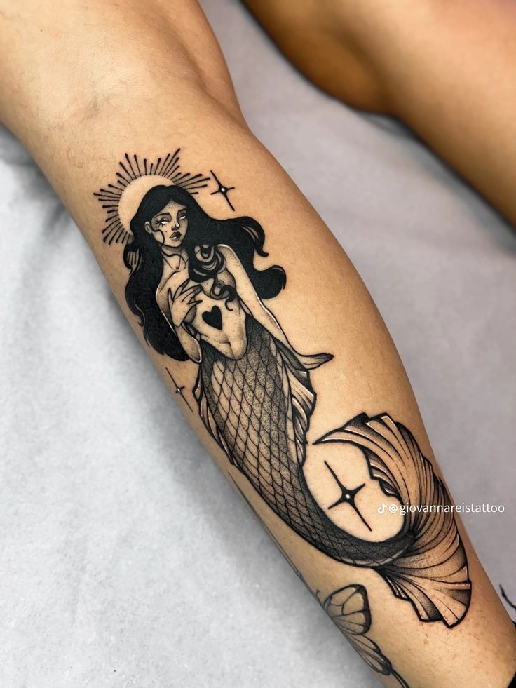 a woman with a tattoo on her arm is holding a fish and the sun above her head