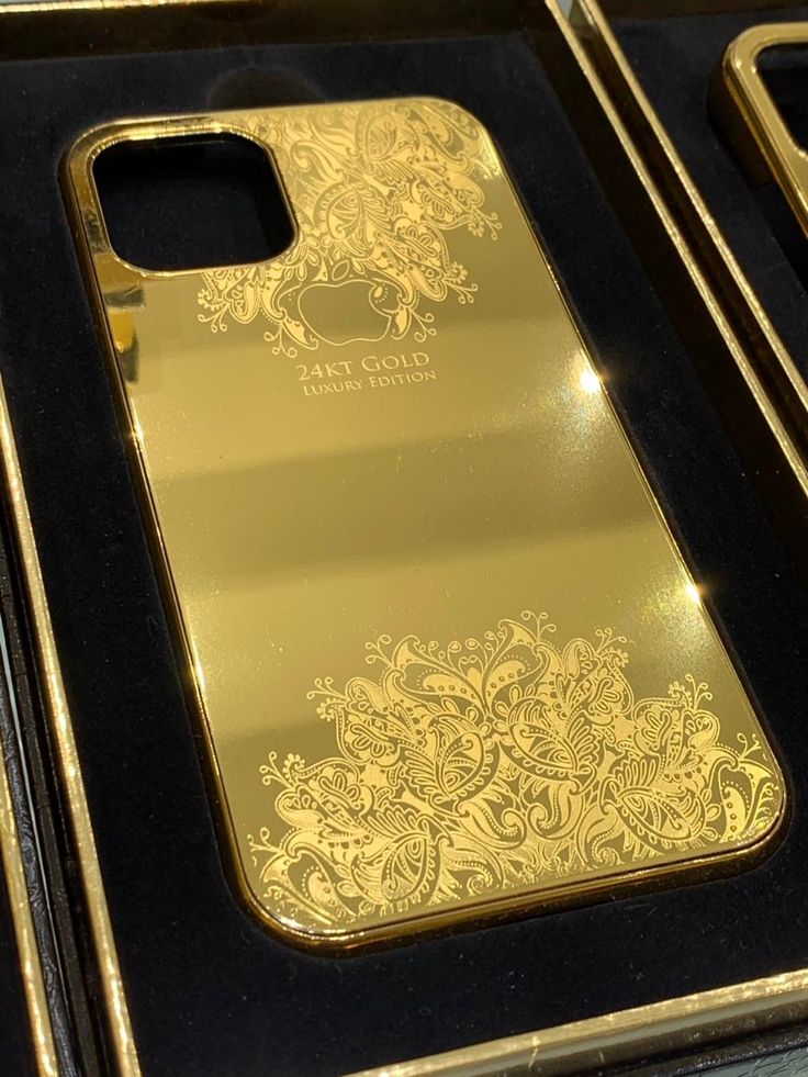 two gold iphone cases sitting on top of a black case in a store display box