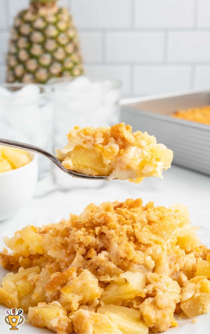 a spoon full of food on top of a white plate next to a pineapple