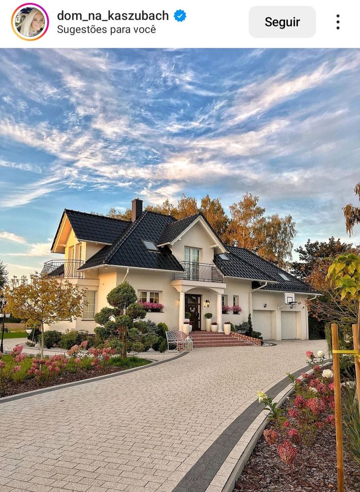 a white house with black roof and landscaping