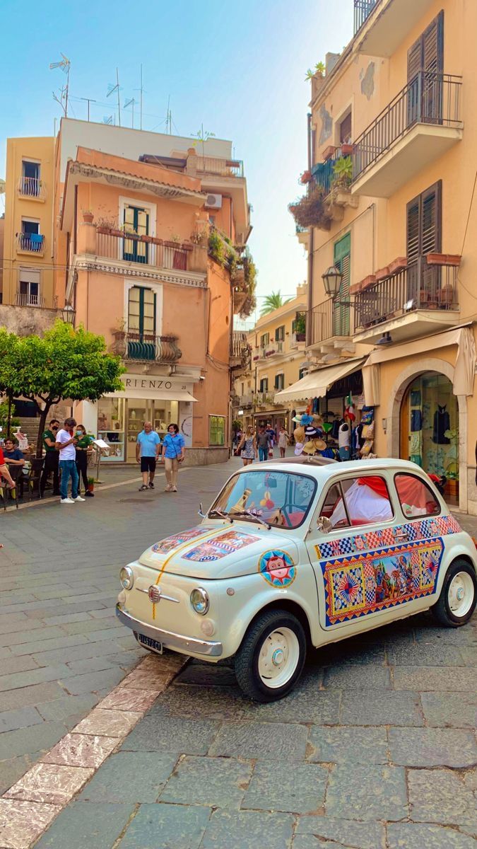 an old car is parked on the side of the road in front of some buildings