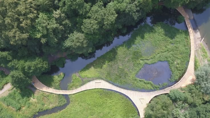 an aerial view of a bridge in the middle of a forest with water running through it