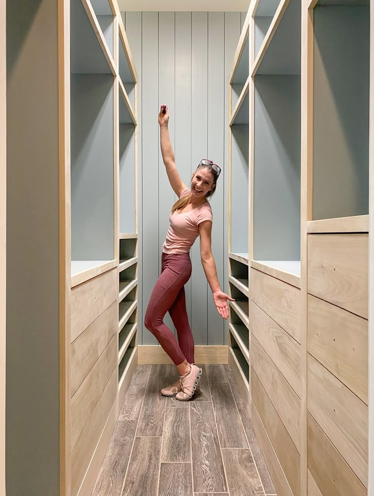 a woman is standing in the middle of an empty walk - in closet with her hand up