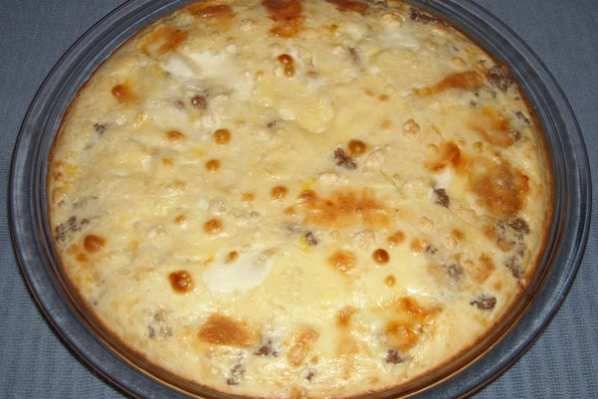 a casserole dish with cheese and meat in it on a blue table cloth