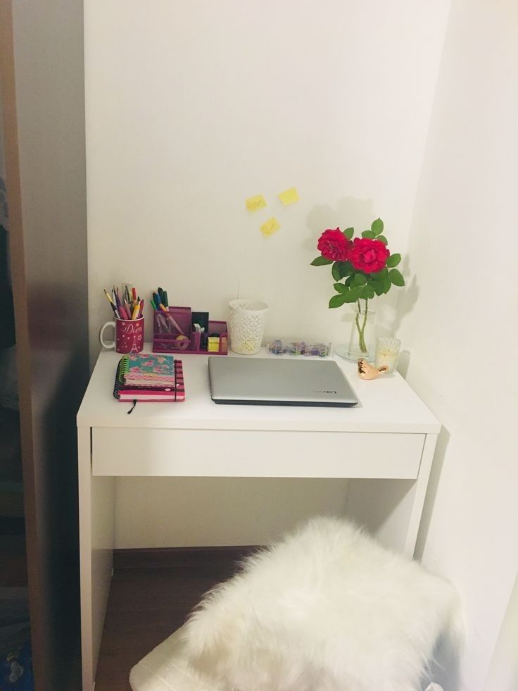 a white desk with a laptop and flowers on it