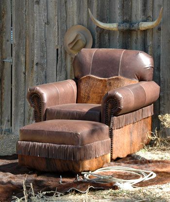 an old leather chair sitting in front of a wooden fence with a cow's head on it