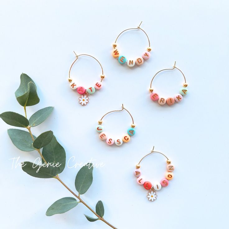 three different types of beaded hoop earrings on top of a branch with green leaves