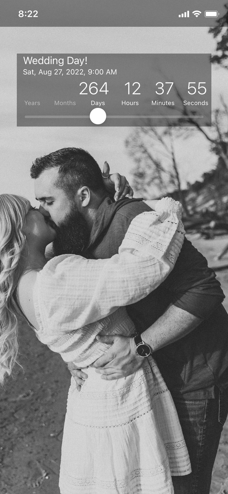 a black and white photo of a couple kissing in front of the camera with their date card