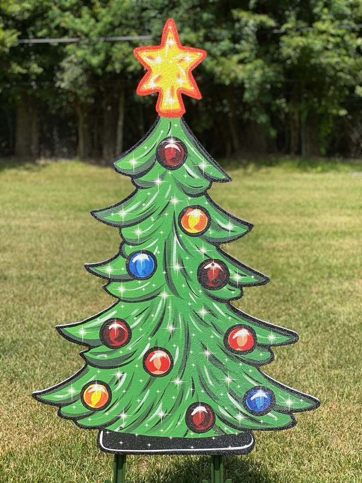 a christmas tree made out of plastic balls in the grass with a star on top