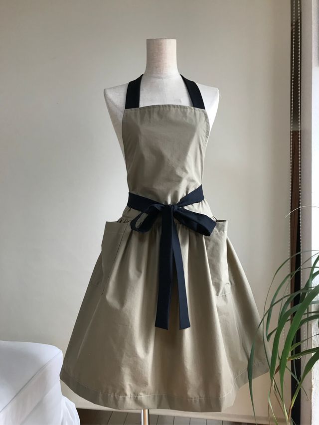 an apron dress is on display in front of a mirror with a potted plant