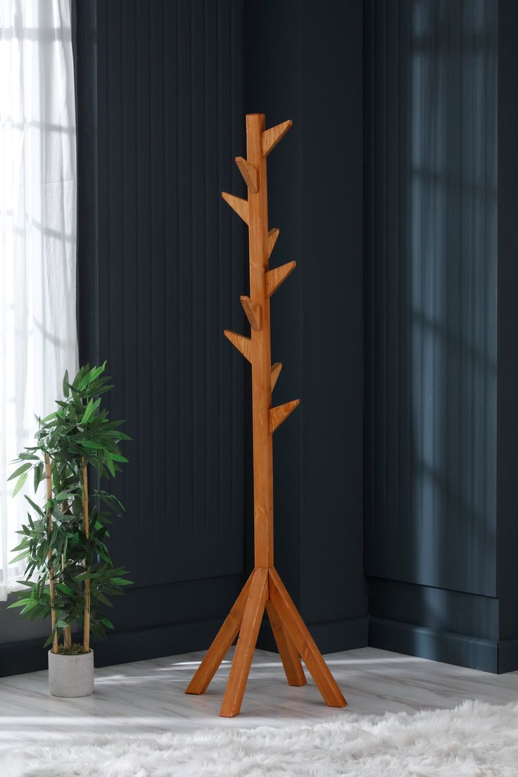 a tall wooden tree stands in front of a potted plant on a white rug