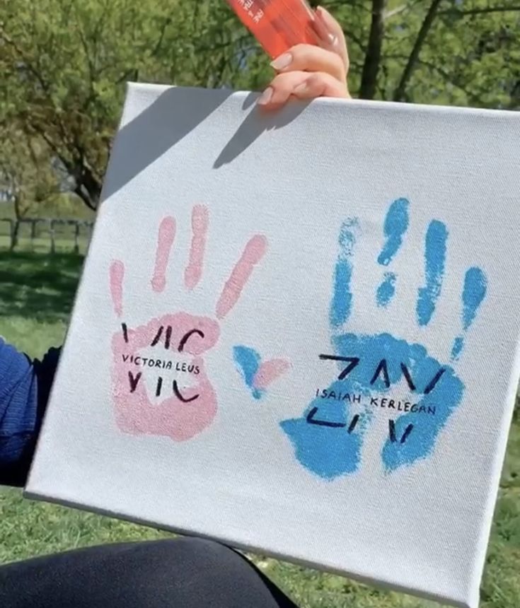 someone holding up a sign with two hand prints on it