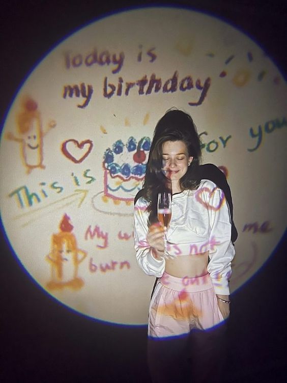 a woman holding a wine glass in front of a birthday cake with writing on it