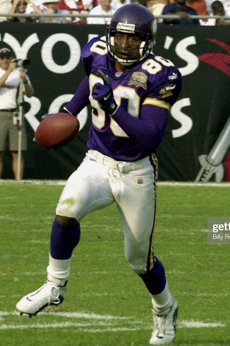 a football player running with the ball in his hand and people watching from the stands behind him