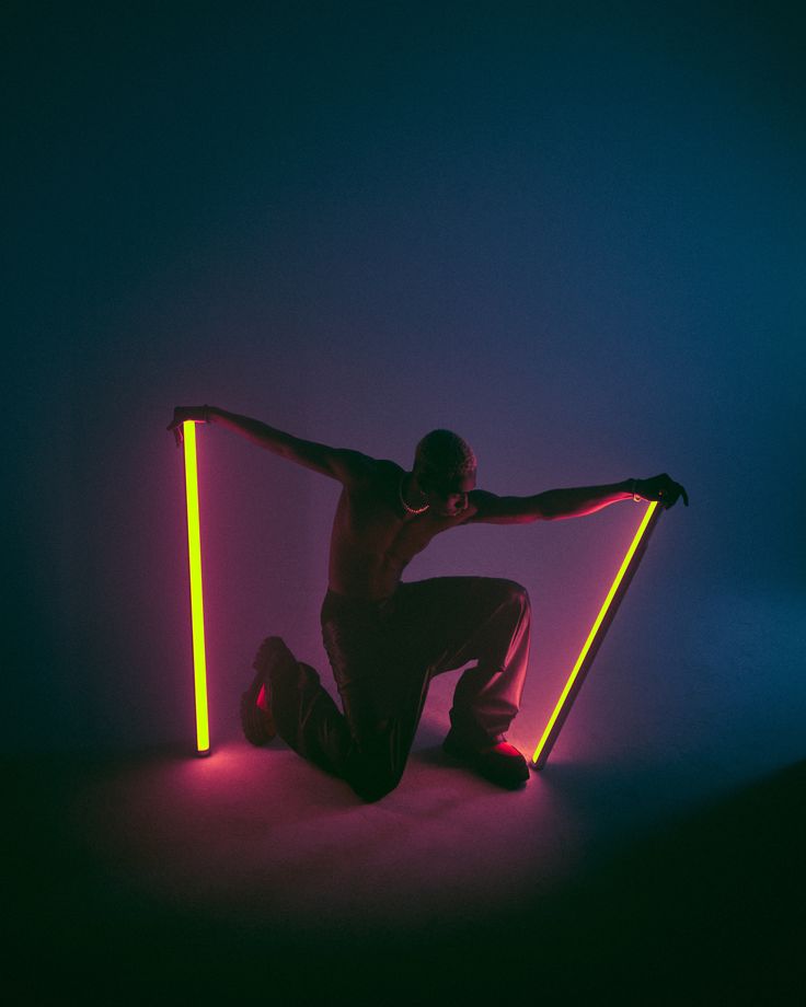 a man sitting on the ground in front of neon lights