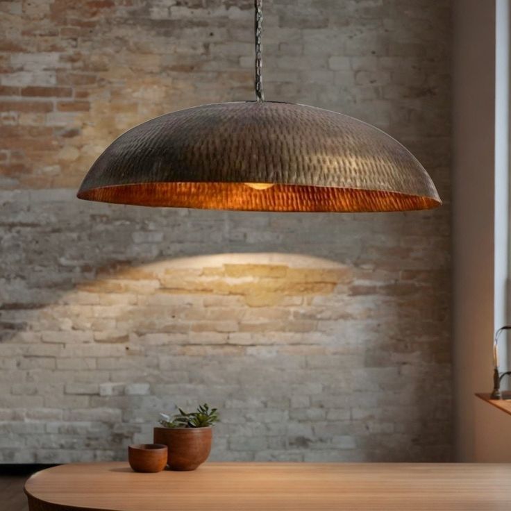 a wooden table with a potted plant on it under a large metal light fixture