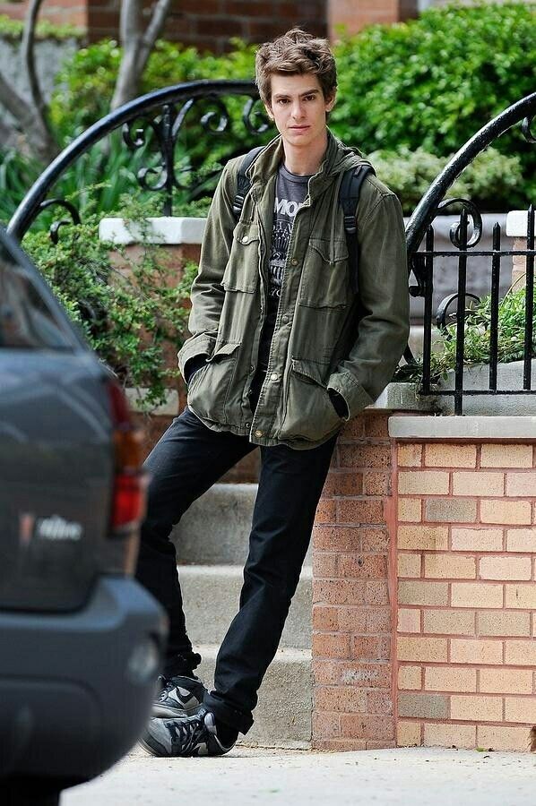 a young man leaning against a brick wall