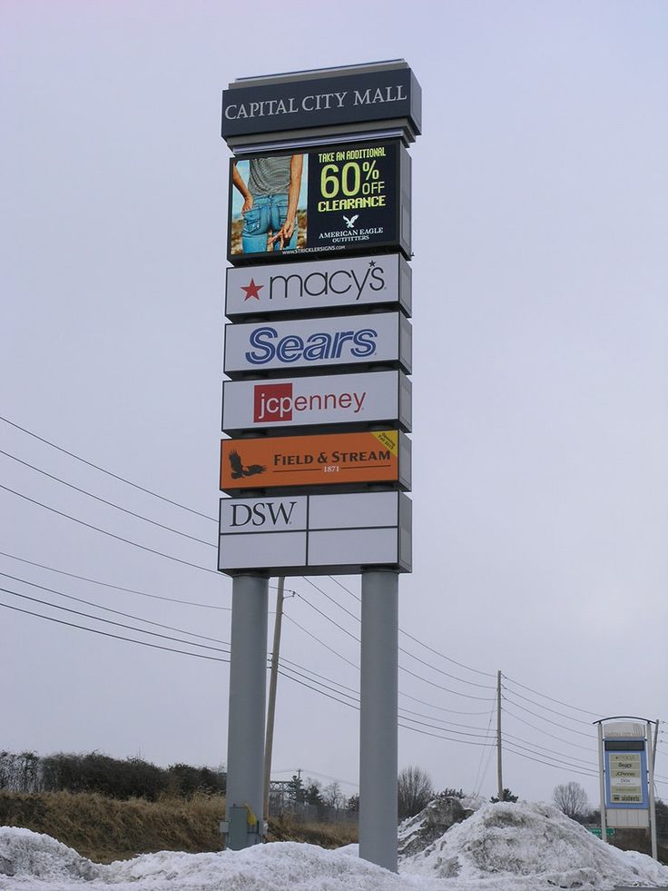 a sign for capital city mall in front of power lines and telephone poles with snow on the ground