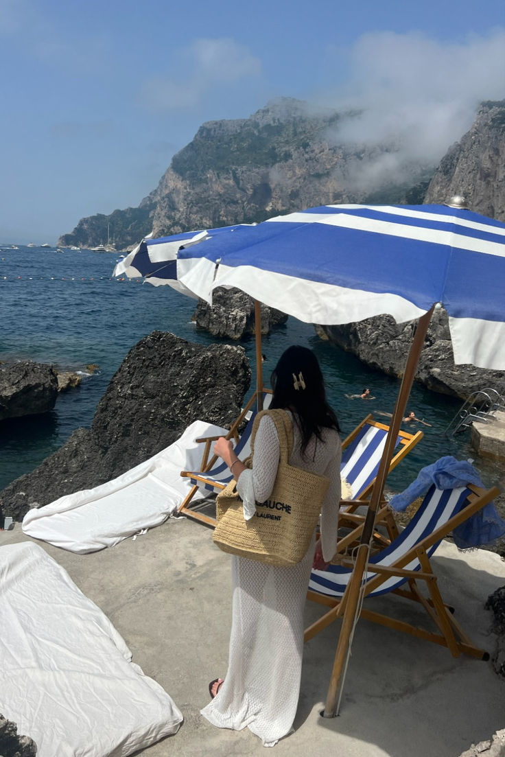 a woman standing under an umbrella next to the ocean