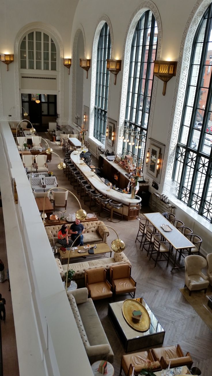 a large room with couches and tables in it's center wall, along with high arched windows