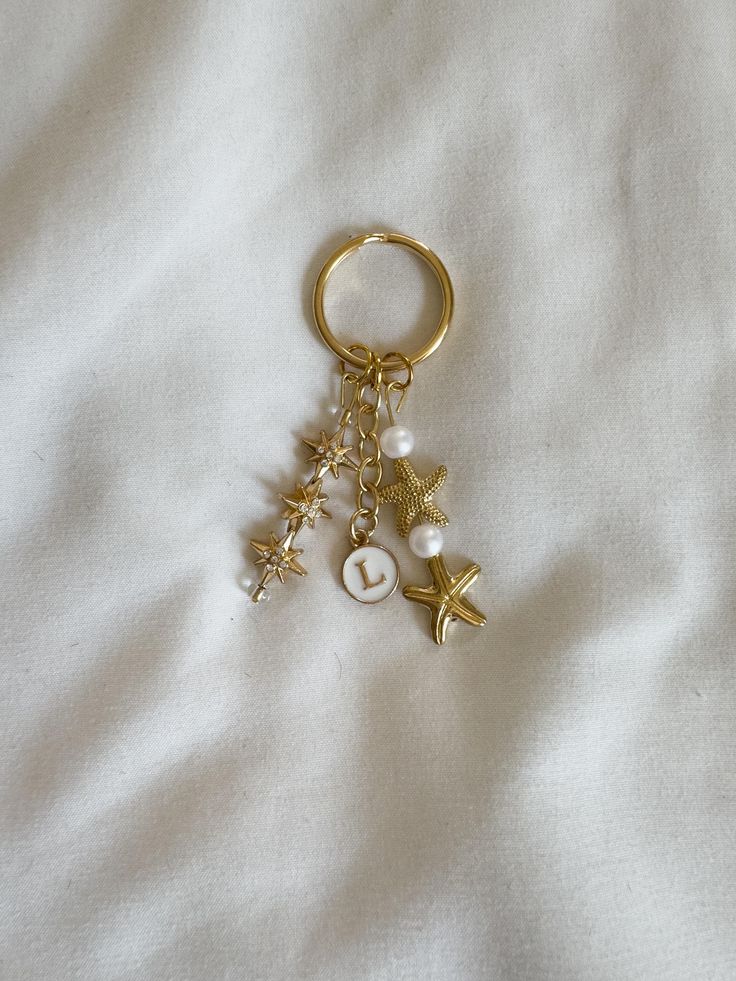 a gold keychain with charms attached to it on a white sheeted surface