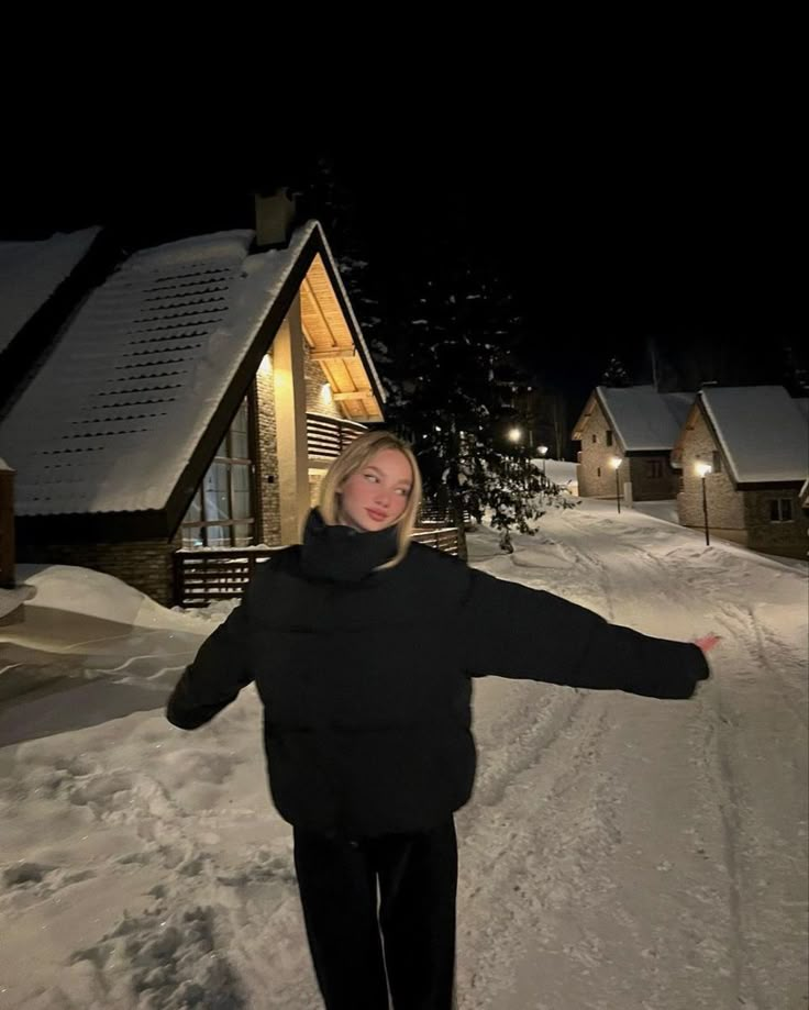 a woman standing in the snow with her arms outstretched