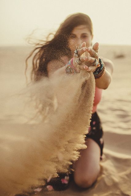 a woman kneeling down in the sand with her hands on her hips and fingers out