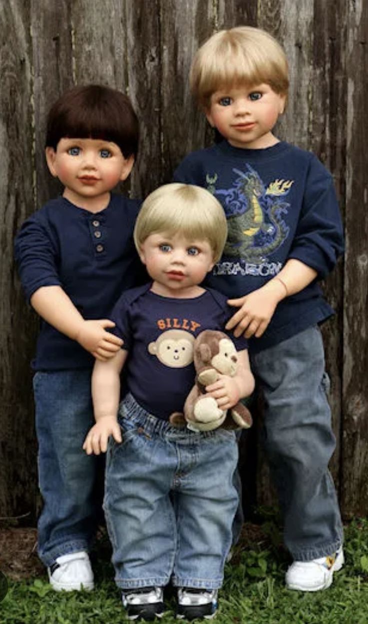 three little boys standing next to each other with stuffed animals in front of a wooden fence