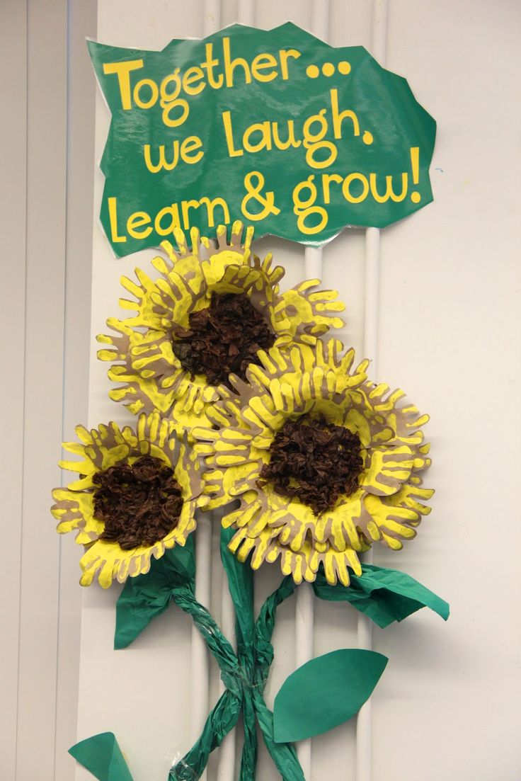 two sunflowers are attached to a sign that says together we laugh, learn and grow