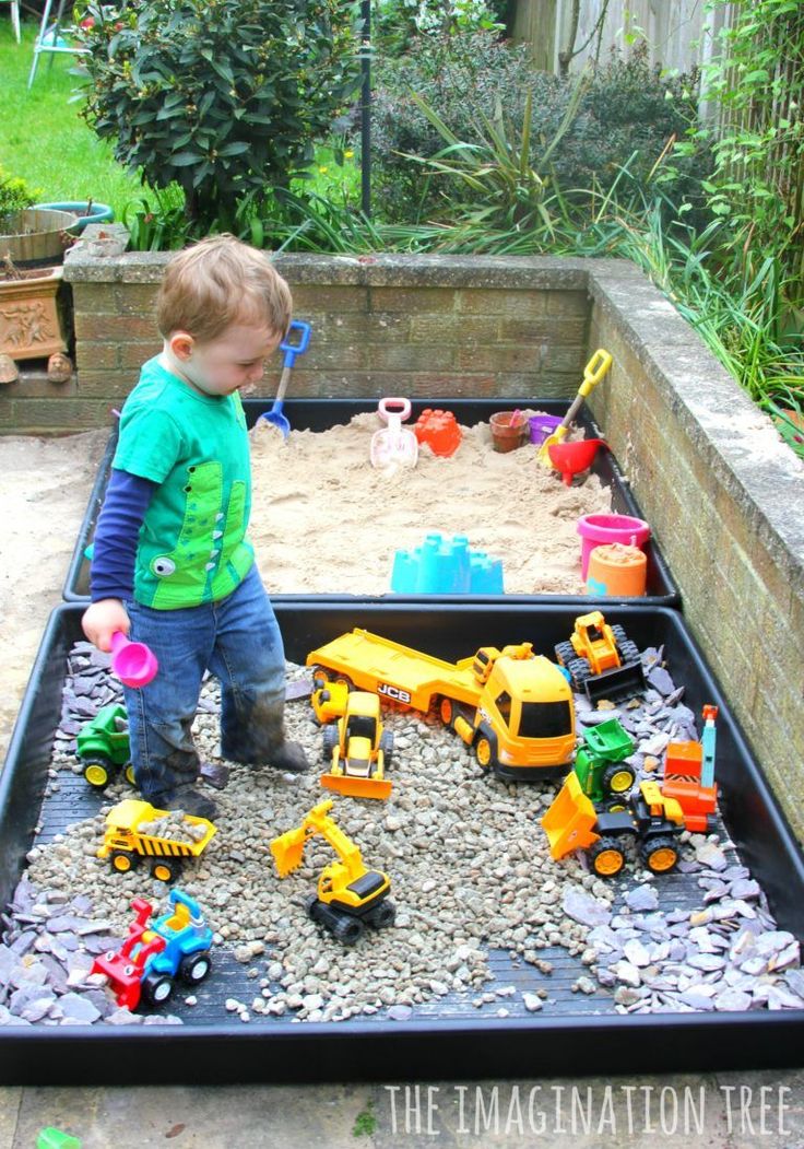 a little boy playing with toys in a sandbox filled with rocks and gravel outside