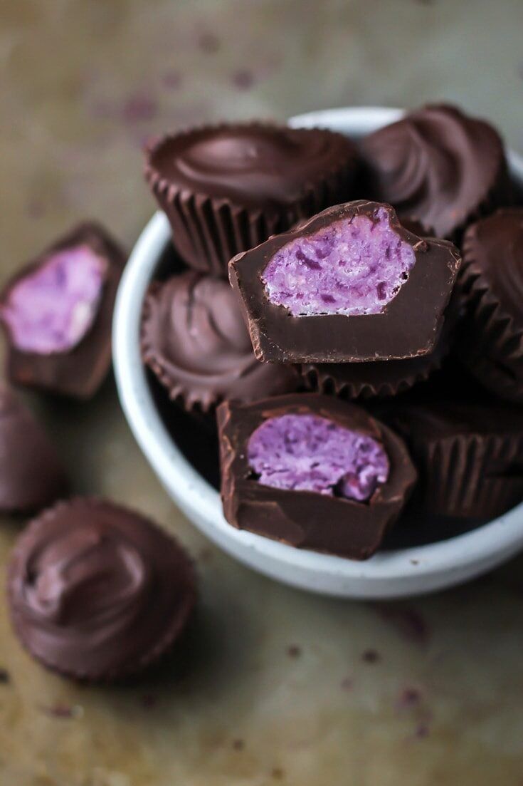 chocolates with purple frosting in a white bowl