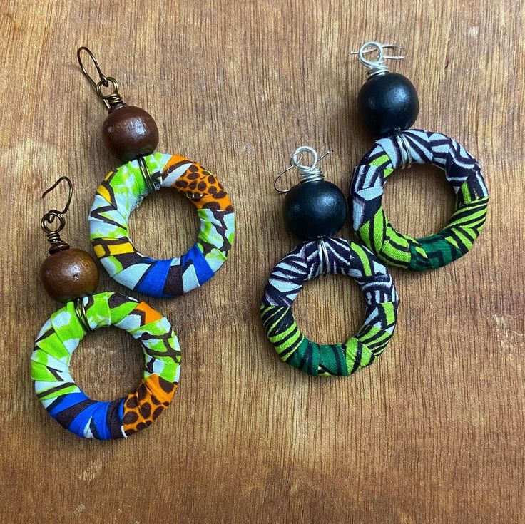 These multi-colored fabric hoop earrings are adorned with a coordinating wood bead. Fabric colors:  *Green/Black/White with Black bead *Blue/Brown/Orange with Brown bead *This item is handmade.  Due to variations in the fabric print, each item may look slightly different from the other. Wood Beaded Earrings, Fabric Hoop Earrings, African Trade Bead Jewelry, Lady Accessories, Africa Earrings, Waist Jewelry, Beading Crafts, Earrings Wood, African Earrings